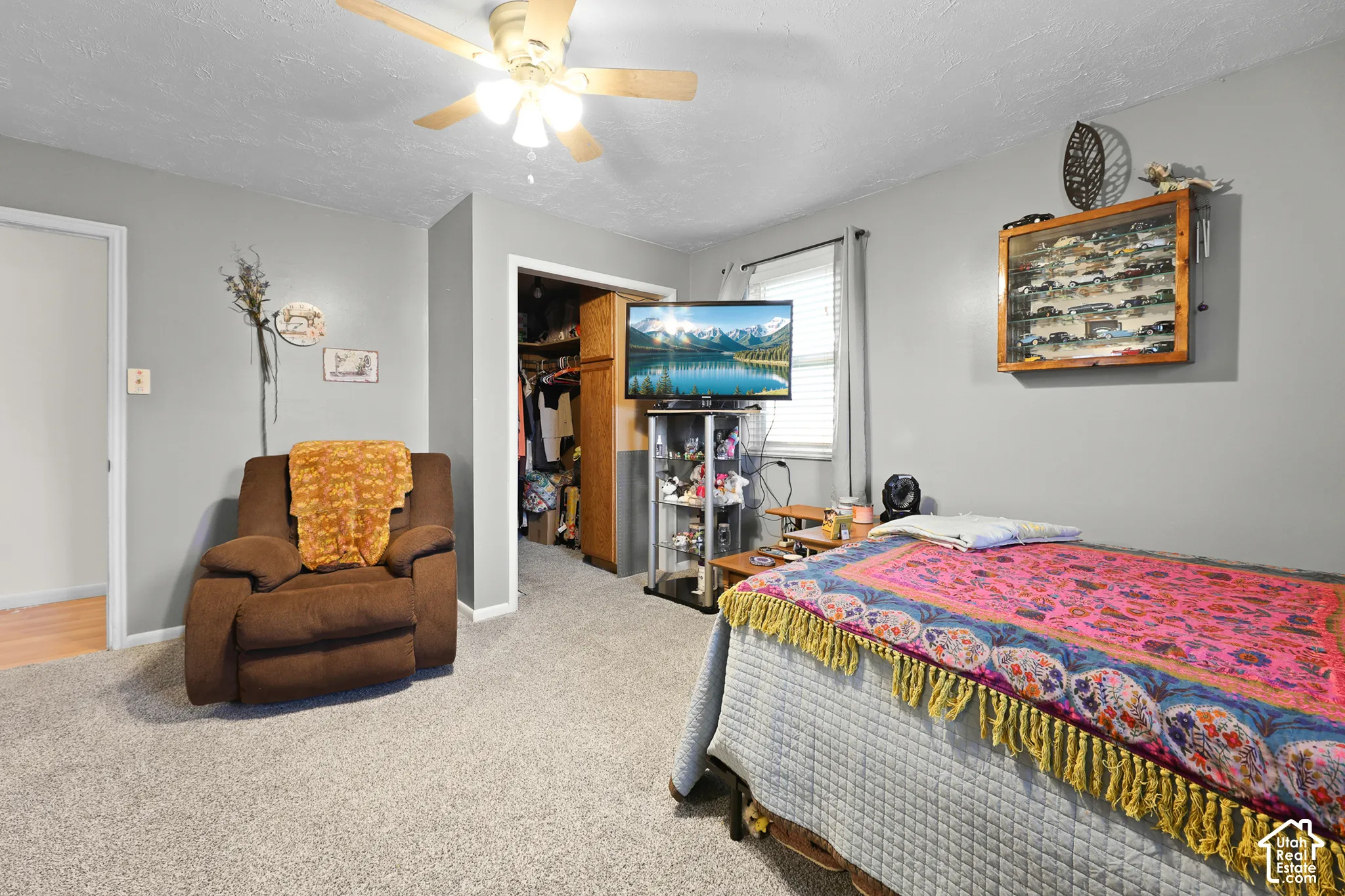 Carpeted room with a ceiling fan, a window with blinds, and a built-in closet with shelving