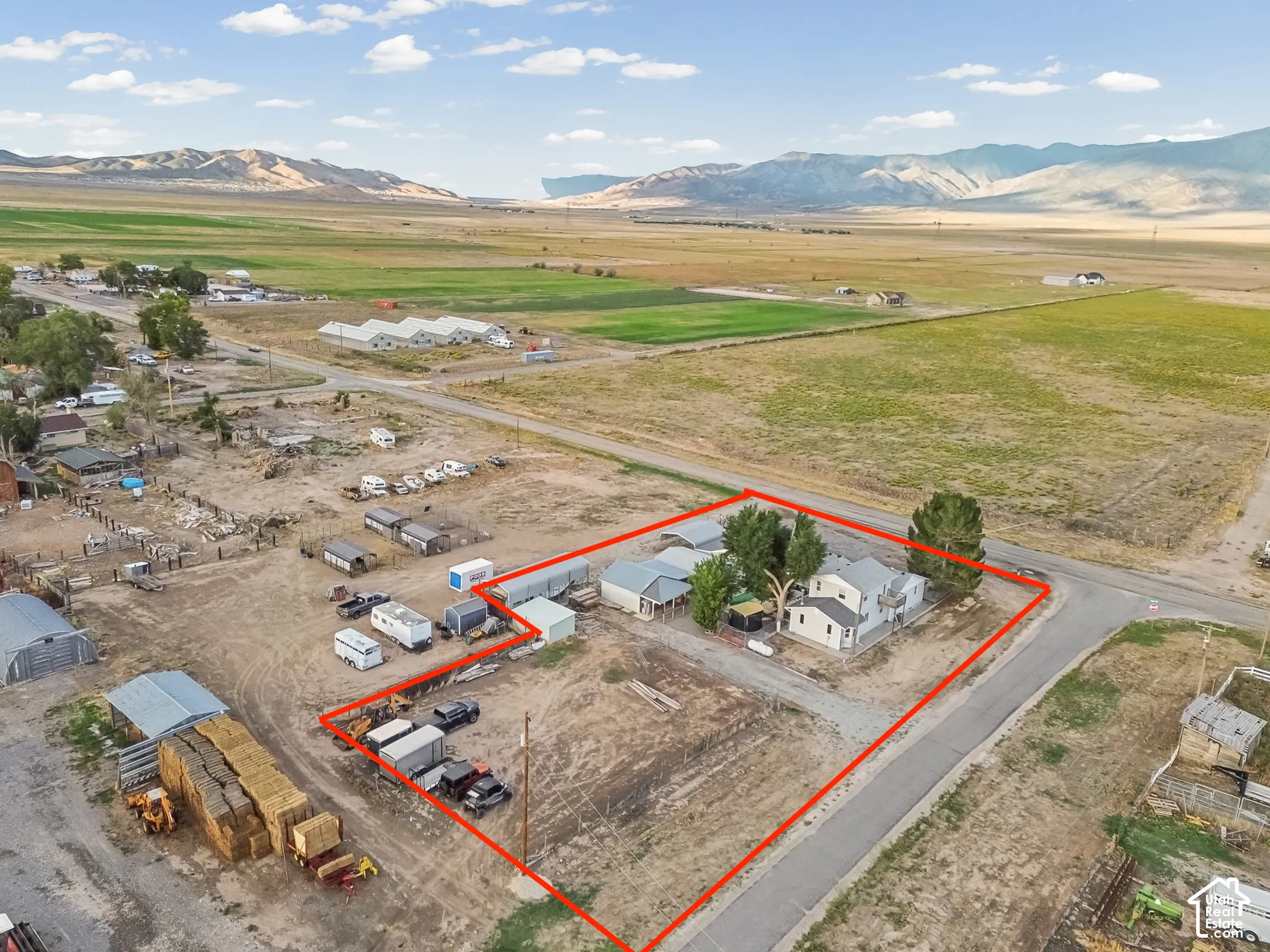 Property boundary highlighted, featuring a two-story home, several outbuildings, and a surrounding open landscape with distant mountains