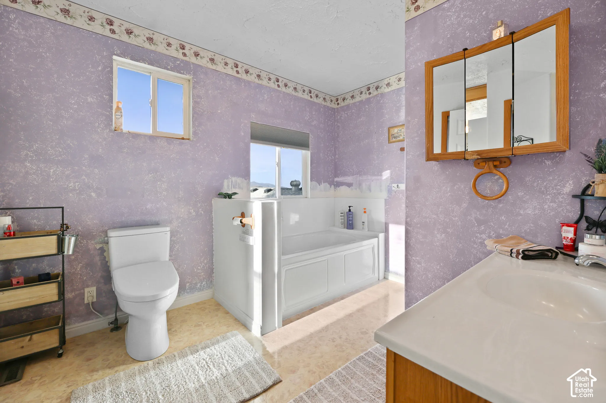 Bathroom featuring a built-in bathtub, a white toilet, and a vanity with an integrated sink