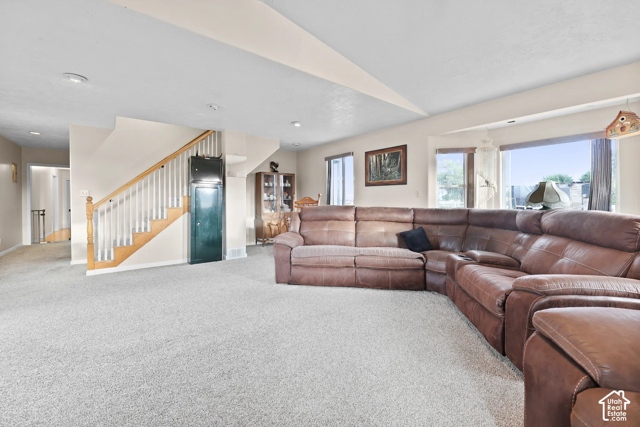 Spacious living area featuring light-toned carpet flooring and a neutral color palette
