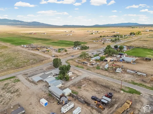 Extensive acreage with multiple structures, including a primary residence with an attached carport, additional outbuildings, and a large open field