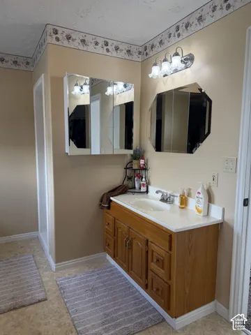 Wood-finish vanity with white countertop and integrated sink, complemented by a tri-mirror medicine cabinet