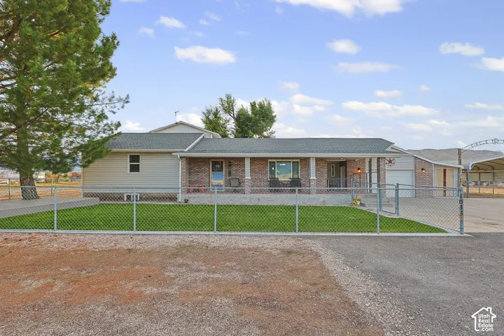 Brick and siding exterior with a covered front porch, attached garage, and a chain-link fence enclosing a front lawn