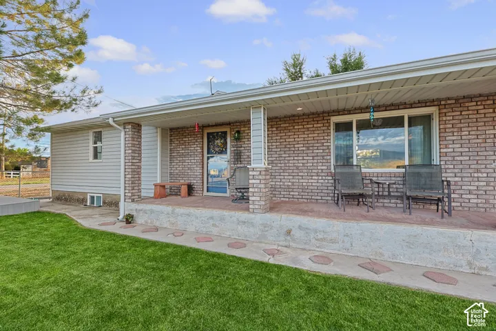 Brick and siding exterior with a covered concrete porch, featuring a manicured lawn and decorative stepping stones