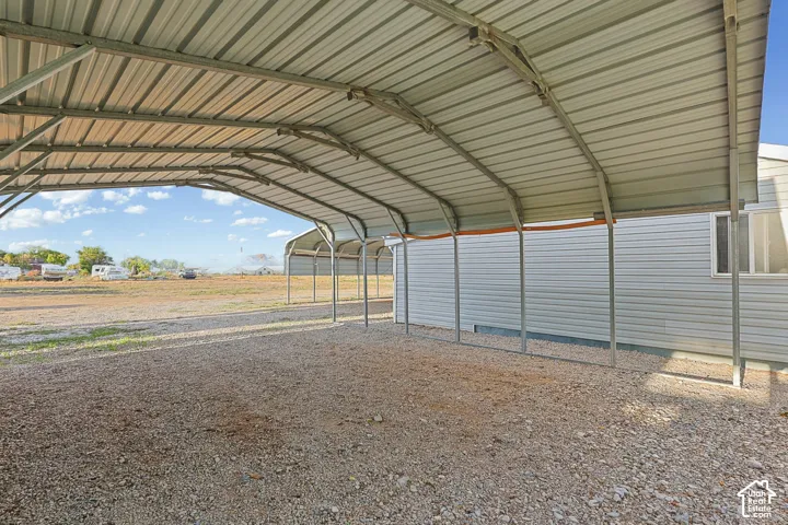 Large metal carport structure with a gravel surface