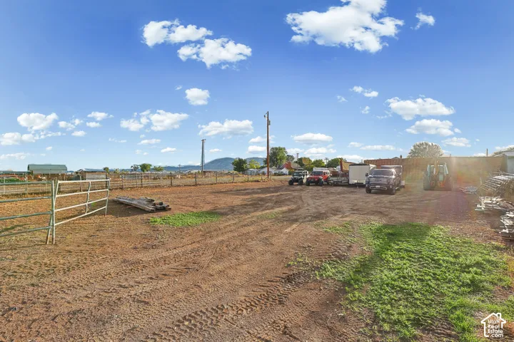 Expansive open dirt area with perimeter fencing, featuring a metal gate and distant structures