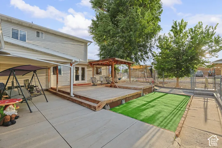 Expansive wood-finish deck with built-in pergola, concrete patio, and artificial turf area