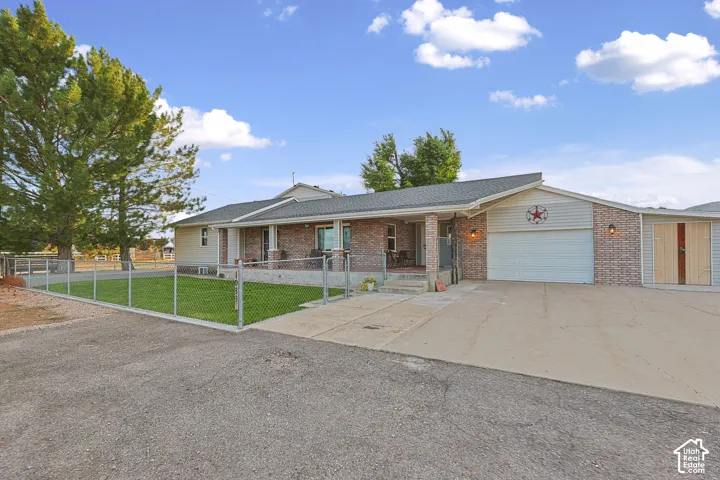 Brick and siding exterior featuring an attached garage, covered front porch, and a fenced lawn area