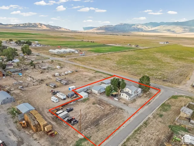 Property boundary highlighted, featuring a two-story home, several outbuildings, and a surrounding open landscape with distant mountains