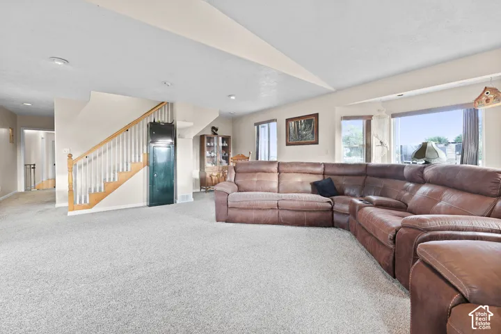Spacious living area featuring light-toned carpet flooring and a neutral color palette