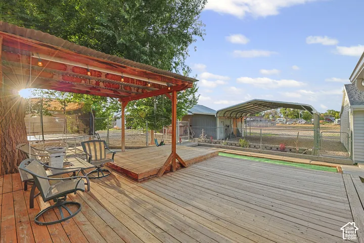 Expansive wood-finish deck with a built-in pergola, outdoor string lighting, and an additional sheltered structure