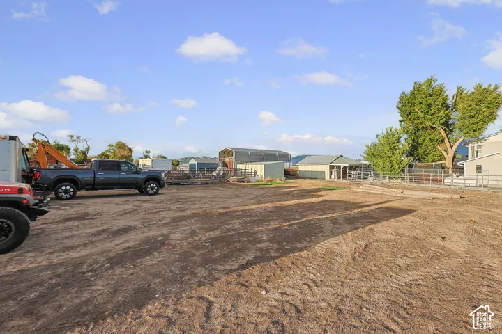 Expansive dirt lot with various outbuildings and mature trees