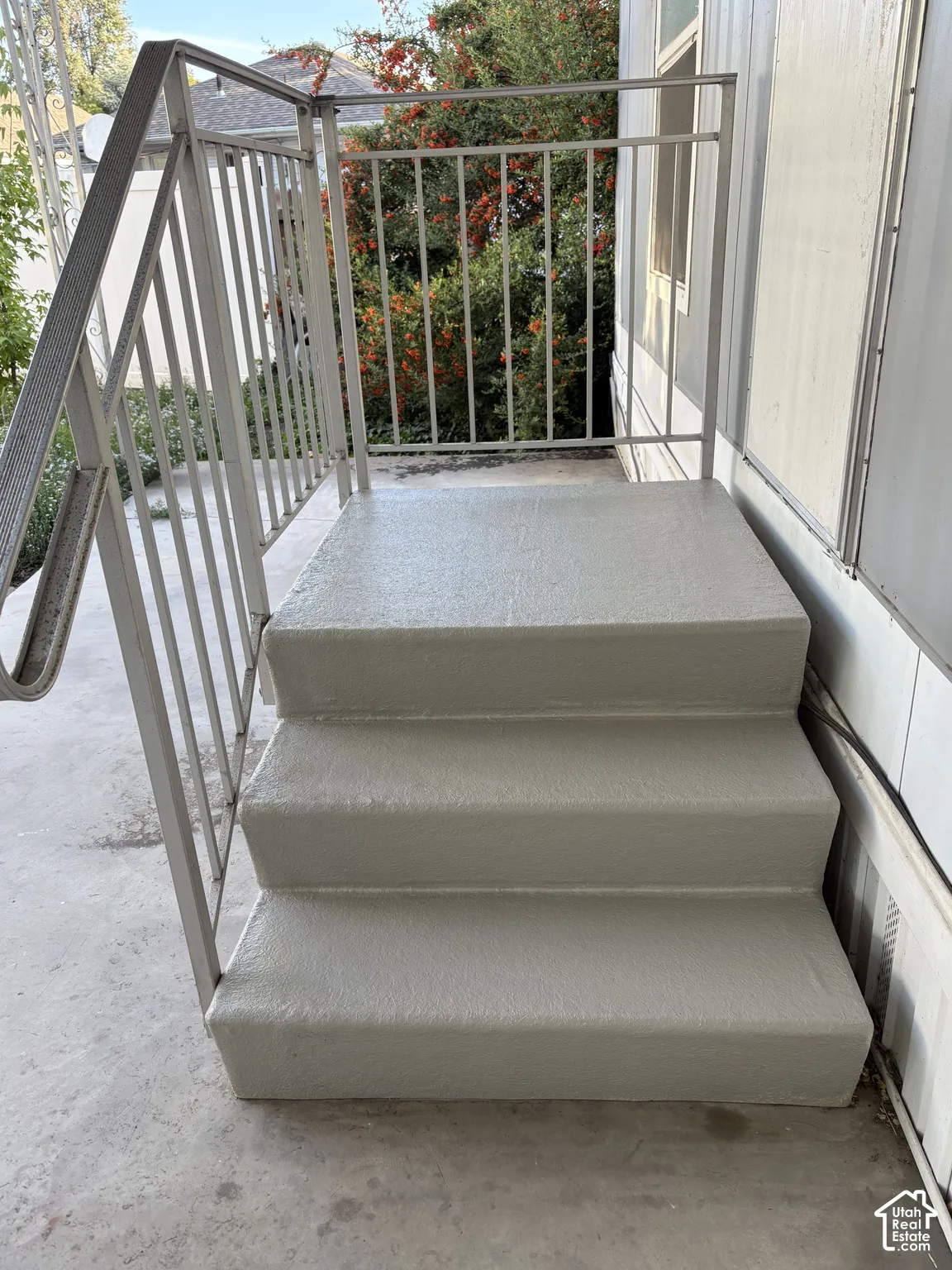 Exterior entrance featuring concrete steps, a metal handrail, and vertical siding