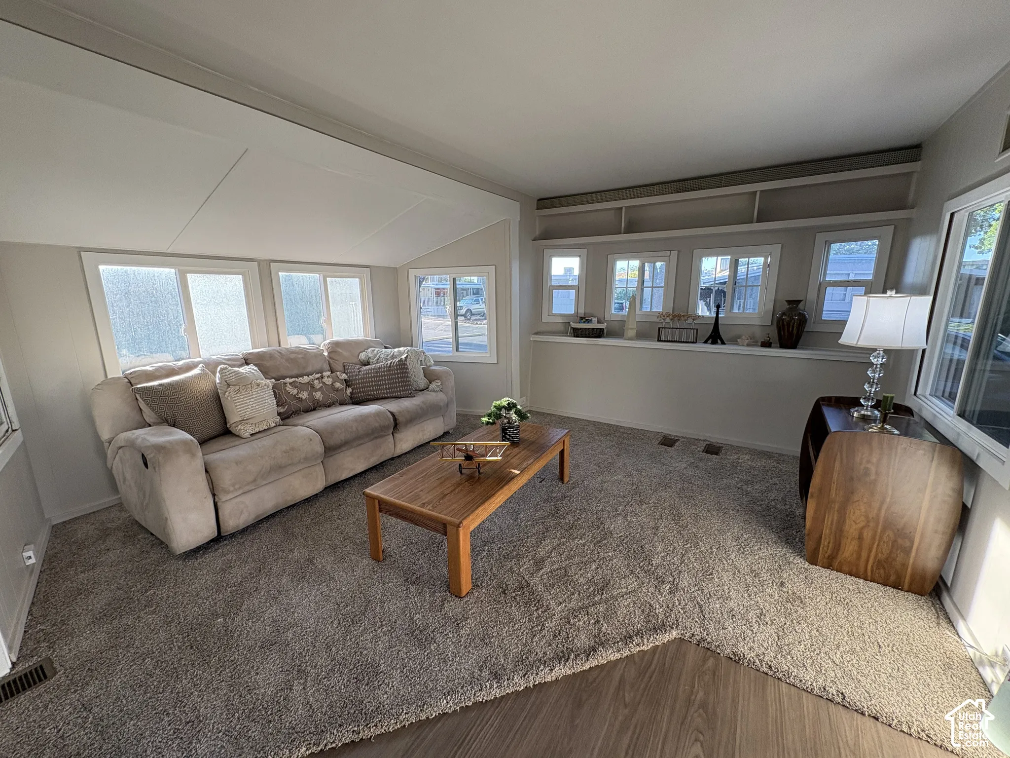 Vaulted ceiling with paneling, multiple transom windows, built-in shelving, wood-finish flooring, and wall-to-wall carpeting