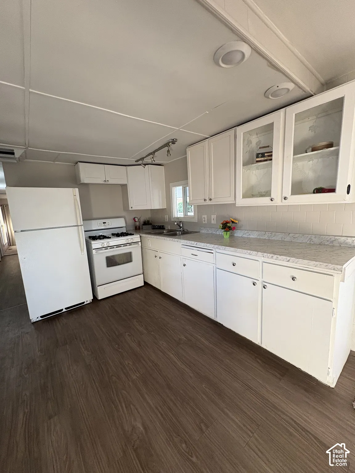 White cabinetry with glass-front upper cabinets, wood-finish flooring, white appliances, and recessed ceiling lighting