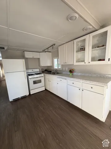 White cabinetry with glass-front upper cabinets, wood-finish flooring, white appliances, and recessed ceiling lighting