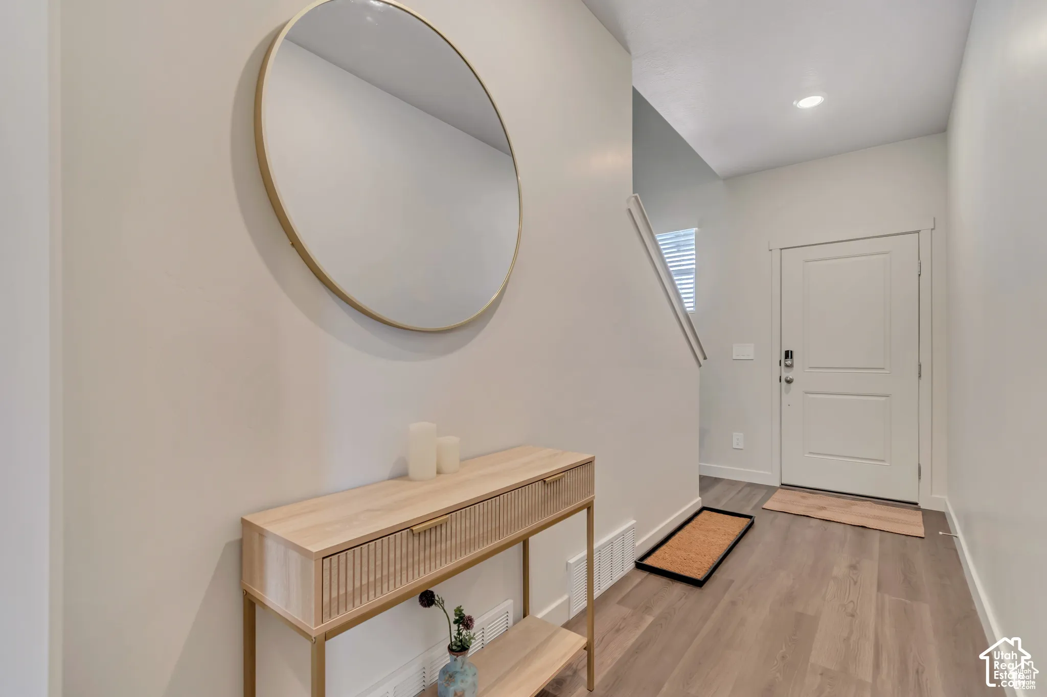 Entryway featuring wood-finish flooring, a contemporary white door, and recessed lighting
