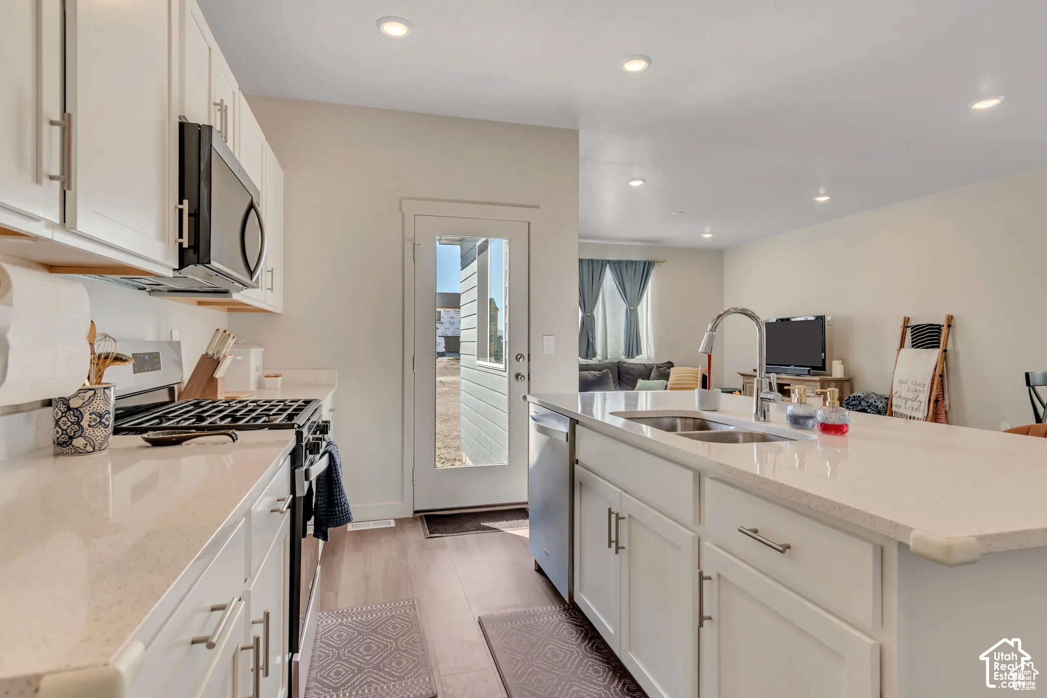 Kitchen featuring white cabinetry, light-toned countertops, a stainless steel sink, a gas range, and recessed lighting