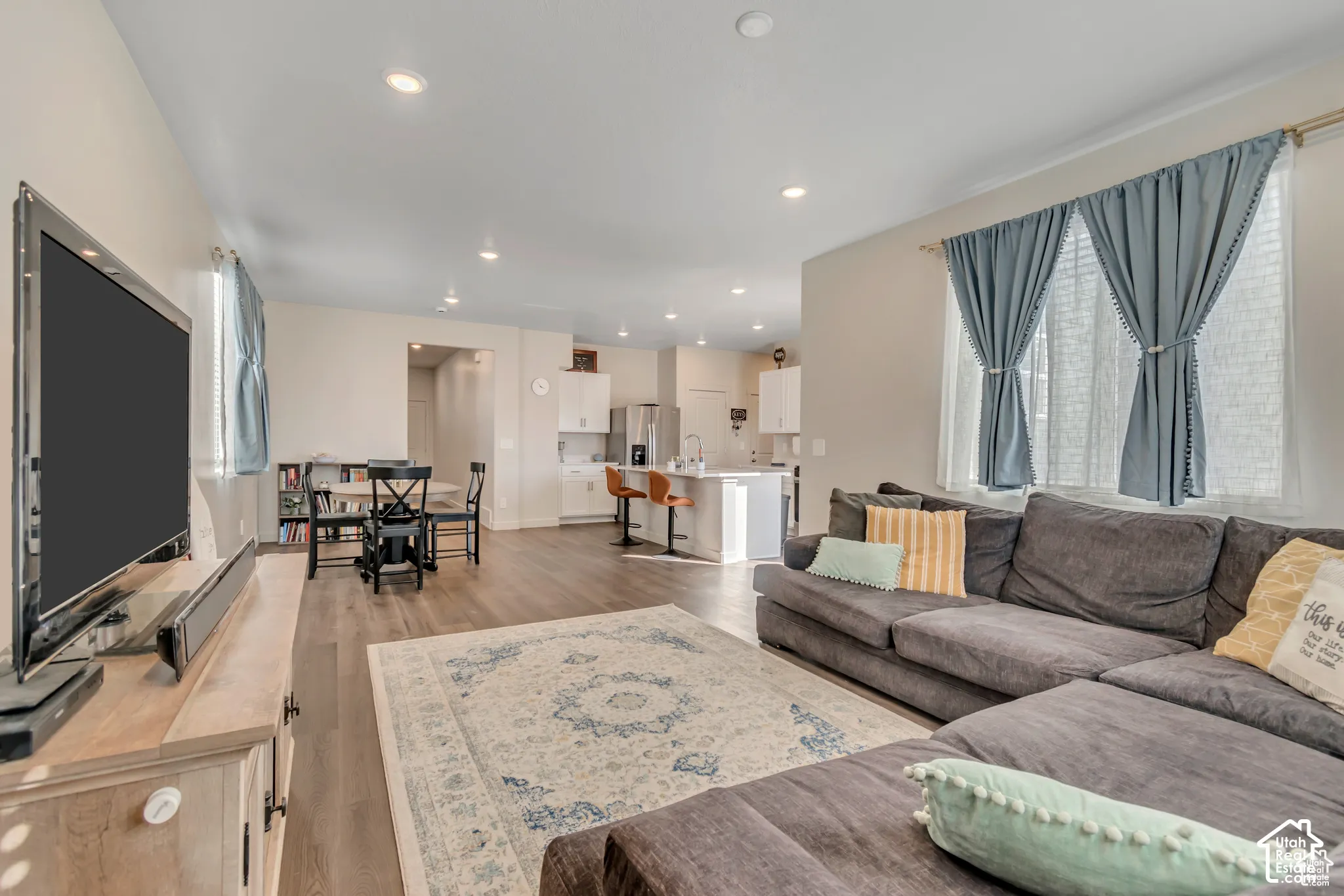 Recessed lighting illuminates the open-concept living area with wood-finish flooring