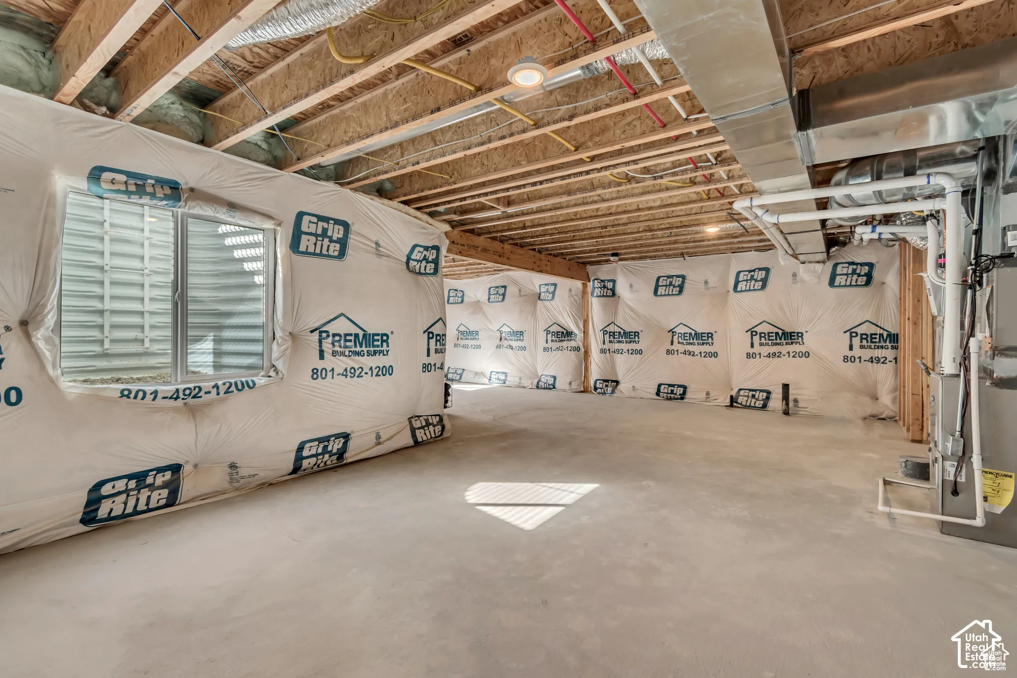 Unfinished lower level with exposed ceiling joists, concrete flooring, and an egress window