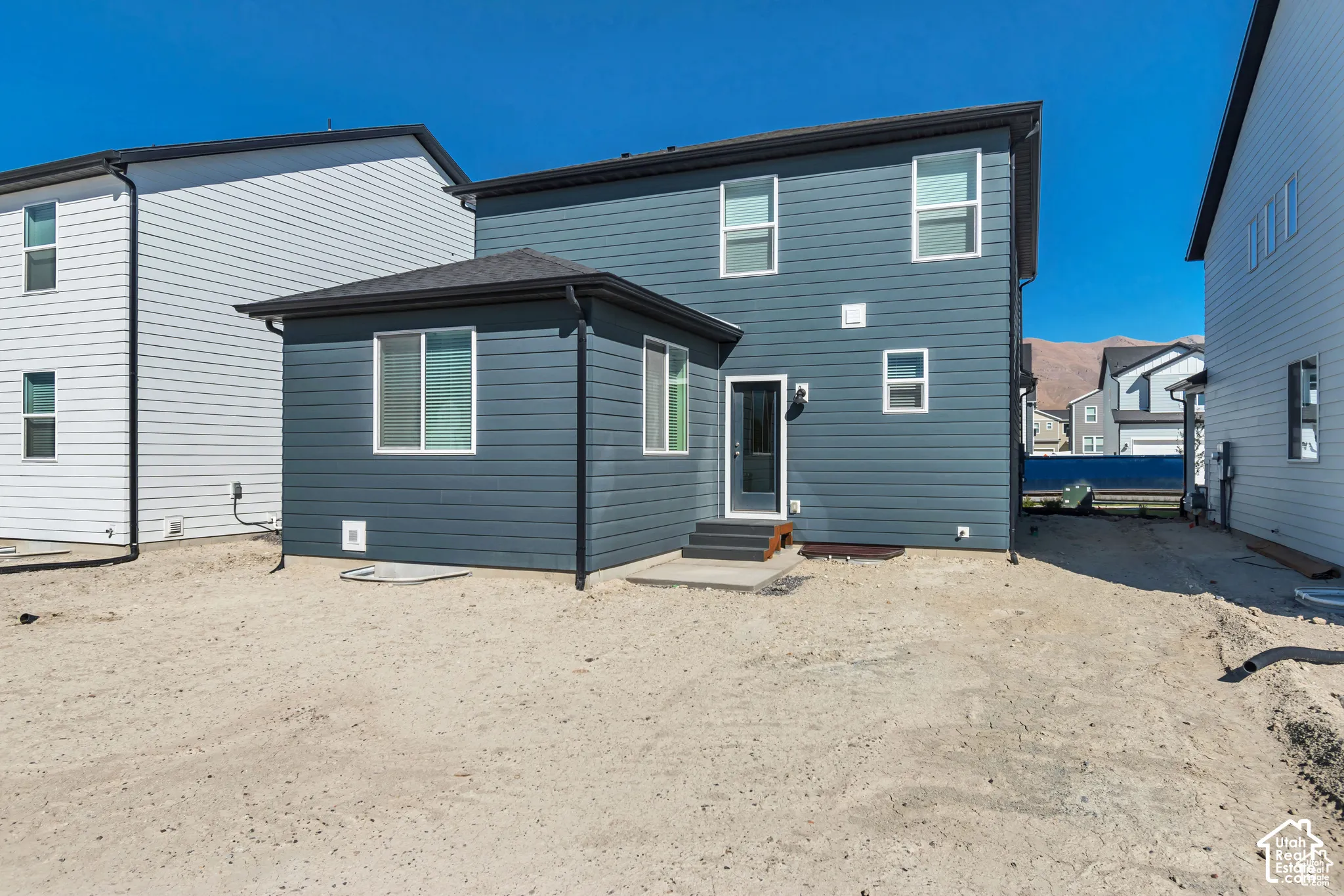 Two-story exterior with horizontal siding, multiple windows, a rear entry door, and a ground-level patio