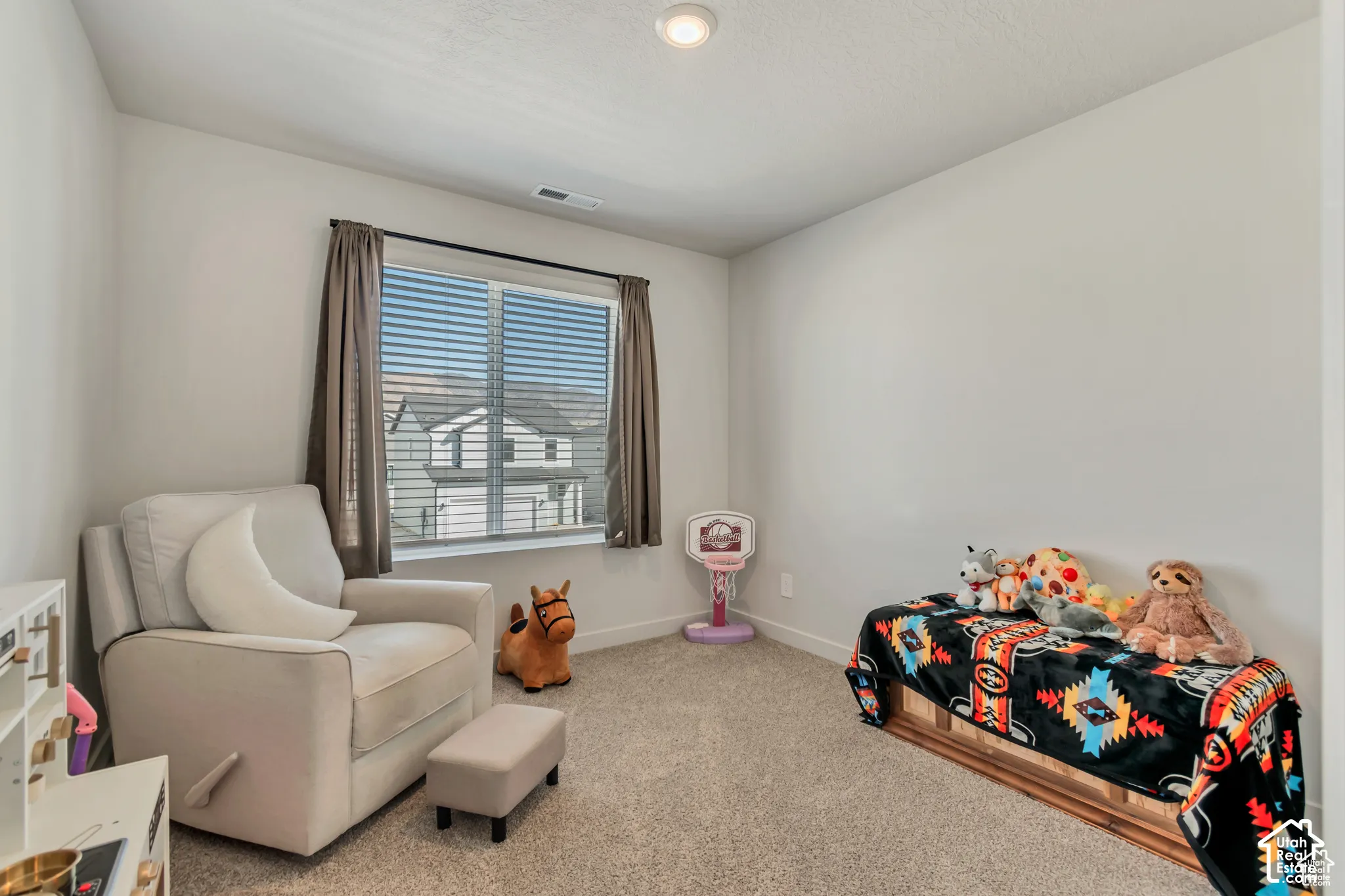 Carpeted room with a recessed ceiling light, window featuring blinds and drapes, and light gray wall paint