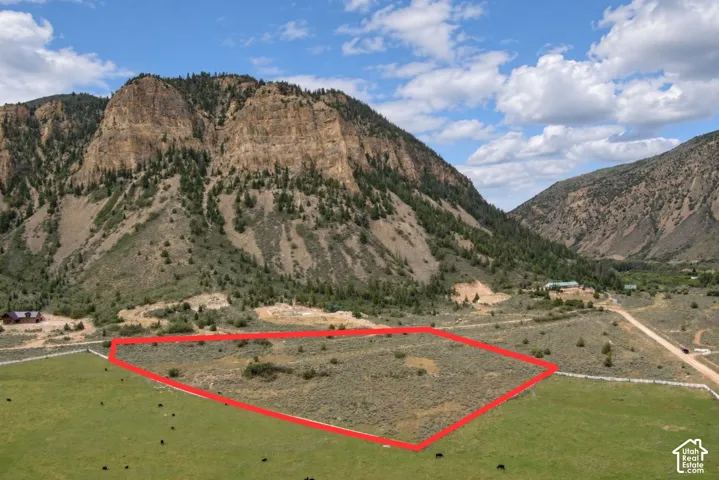 Expansive land parcel with surrounding rugged mountainous terrain and distant valley features