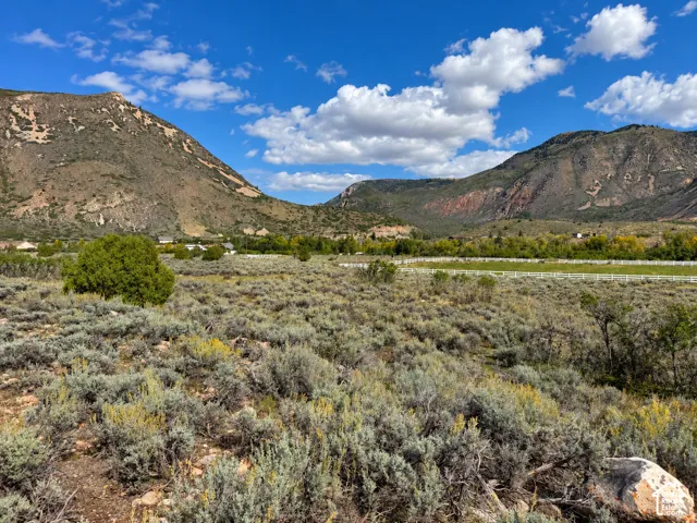 Expansive landscape featuring natural sagebrush, distant mountains, and a white fence line