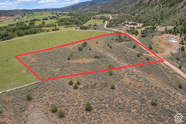 Expansive undeveloped land with a partial grass border and mountainous terrain