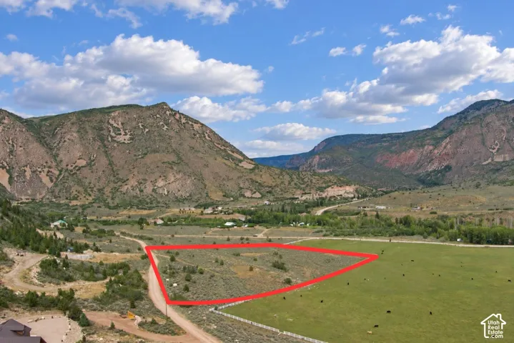 Expansive land parcel featuring natural ground cover, a graded path, and surrounding mountainous terrain