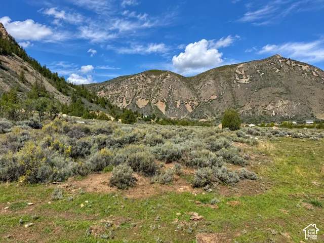Expansive terrain featuring natural ground cover, distant mountainous landscape, and a partly cloudy sky