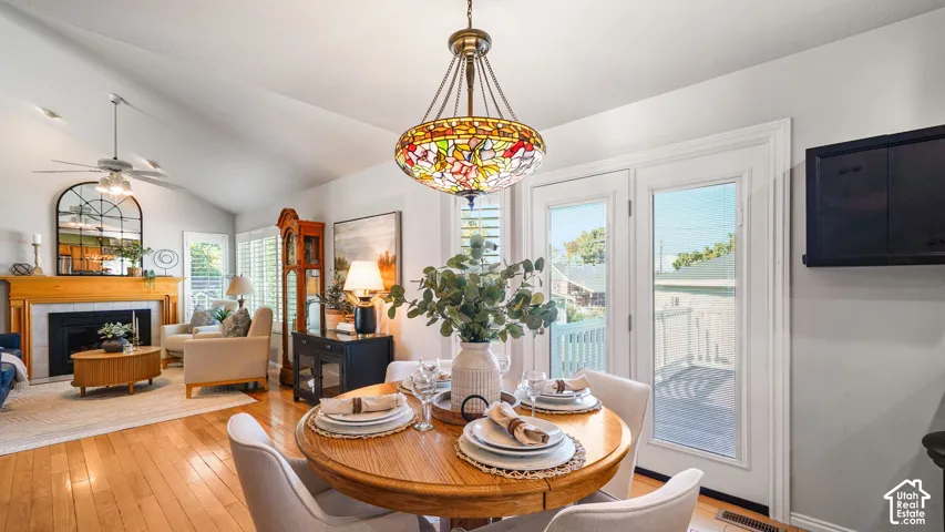Bright open-concept dining and living area featuring hardwood flooring  with seating for six, and abundant natural light from multiple glass doors and windows