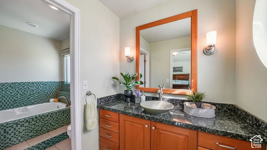 Granite-look countertop with a vessel sink, wood-finish vanity, and a large framed mirror
