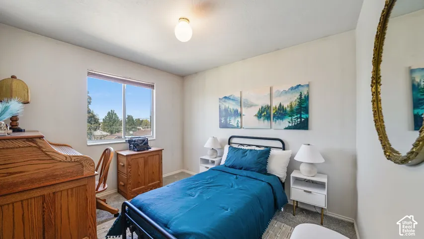Carpeted bedroom featuring a large window, a ceiling-mounted light fixture, and neutral wall tones