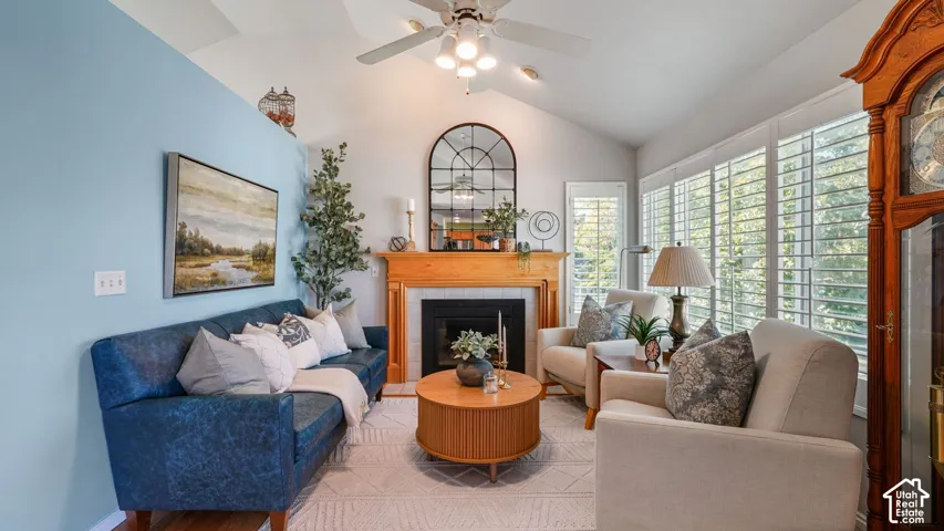 Vaulted ceiling with ceiling fan, wood-finish mantel and fireplace, and plantation shutters