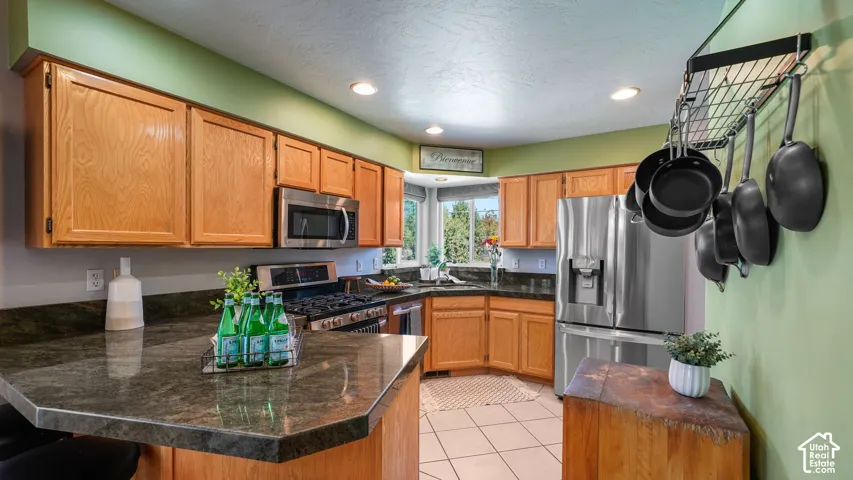 Light wood cabinetry, stainless steel appliances, quartz countertops, recessed lighting, and tile flooring