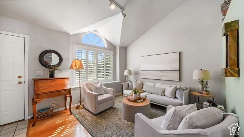 Vaulted ceilings, wood-finish flooring, and arched window with plantation shutters