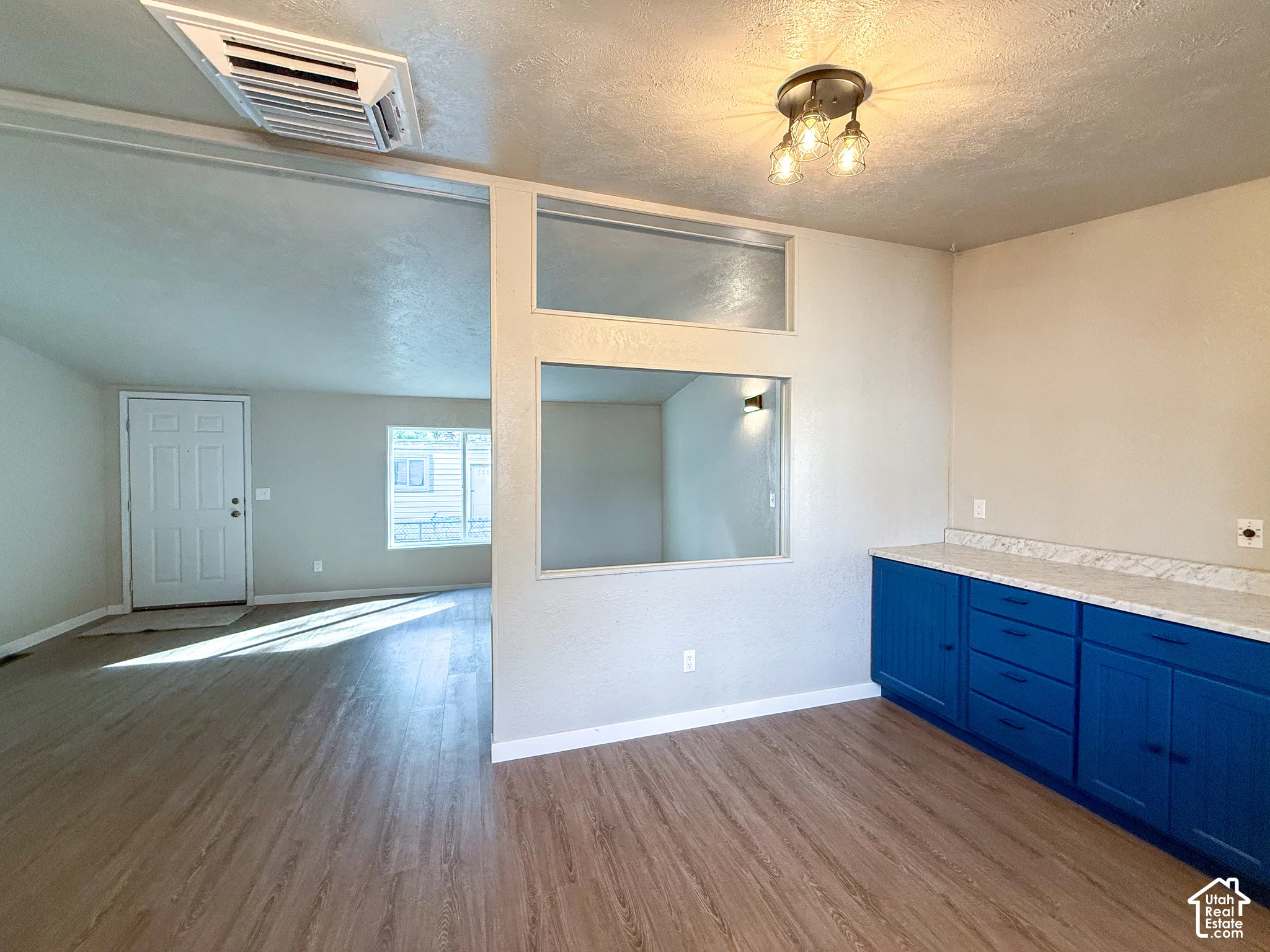 Wood-finish flooring throughout, bright blue lower cabinetry, white countertop, and a semi-flush mount ceiling fixture