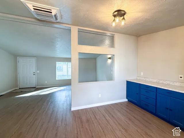 Wood-finish flooring throughout, bright blue lower cabinetry, white countertop, and a semi-flush mount ceiling fixture