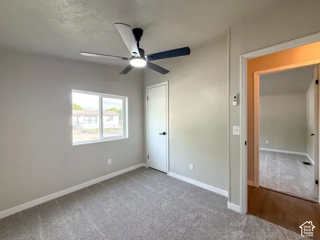 Recessed window with white trim, modern ceiling fan with integrated lighting, light-toned carpeting, and a white interior door with dark hardware