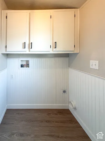 White cabinetry with black hardware, wood-finish flooring, and white wainscoting