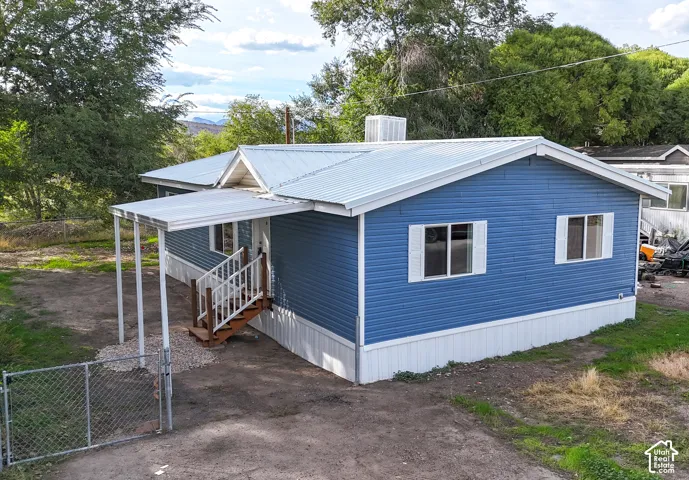 Blue siding with white trim, a covered entryway, a metal roof, and white window shutters