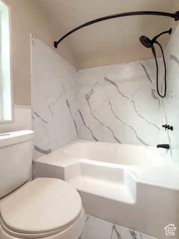 White bathtub with a patterned tile surround, matte black fixtures, and a curved shower rod