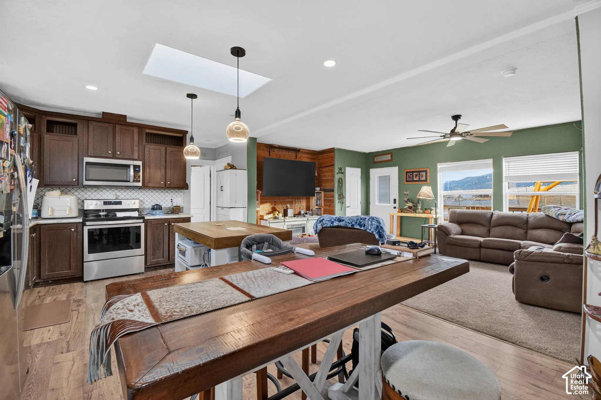 Kitchen featuring stainless steel appliances, dark wood cabinetry, white subway tile backsplash, and wood-finish flooring