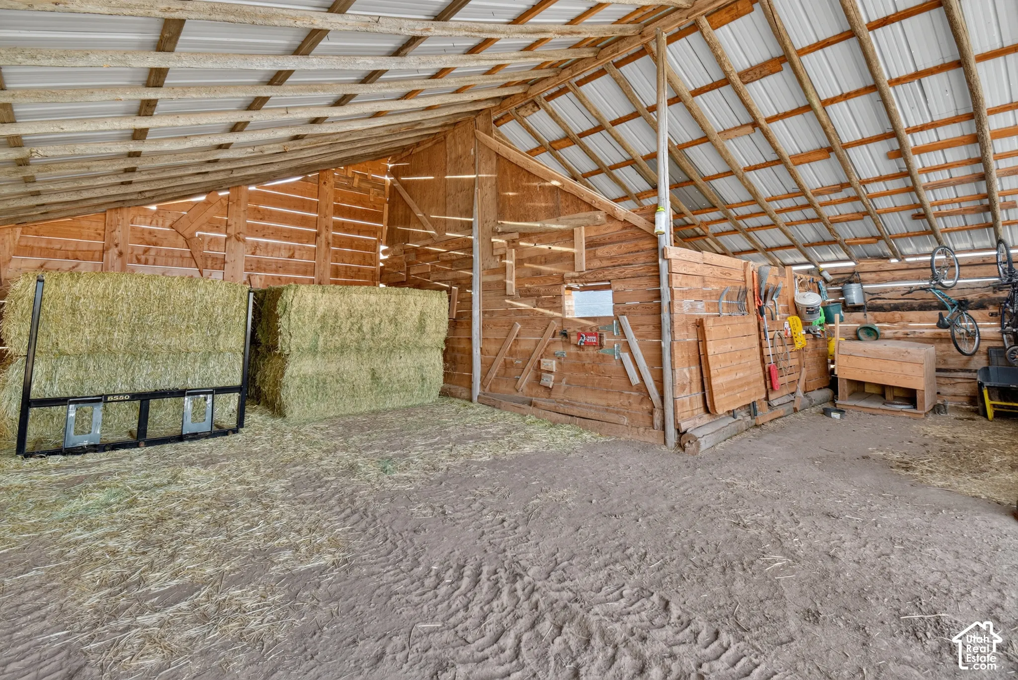 Interior barn structure featuring a corrugated metal roof and exposed wooden beams