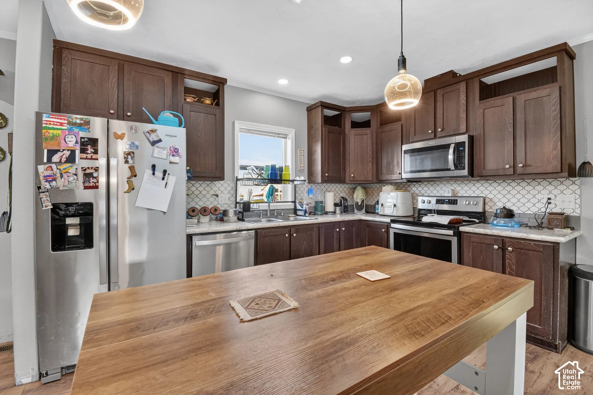 Kitchen featuring wood-finish cabinetry, stainless steel appliances, a tile backsplash, and a wood-finish island
