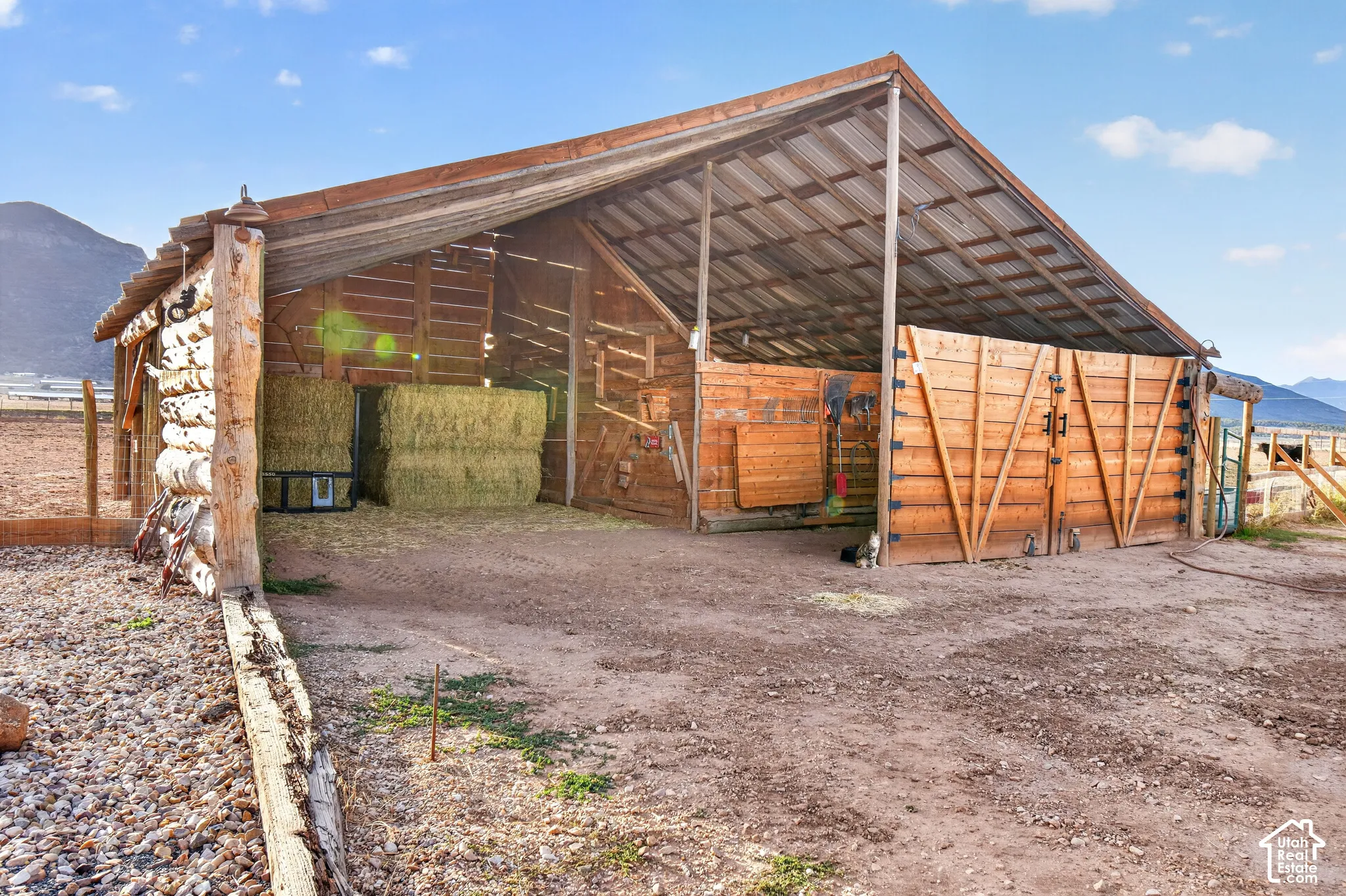 Rustic barn structure with a corrugated metal roof, log construction, and wood-paneled doors