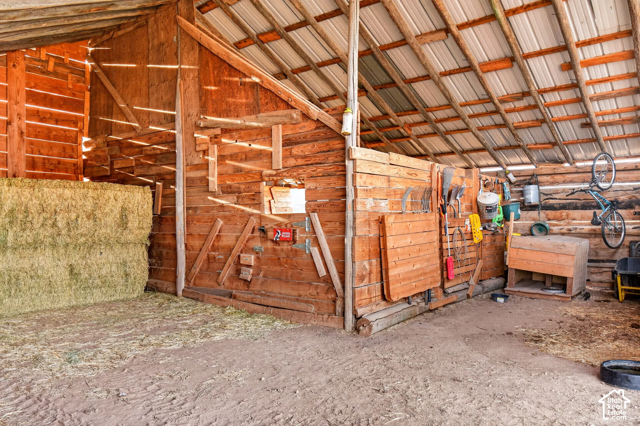 Barn interior featuring wood plank construction, exposed support beams, and a metal roof