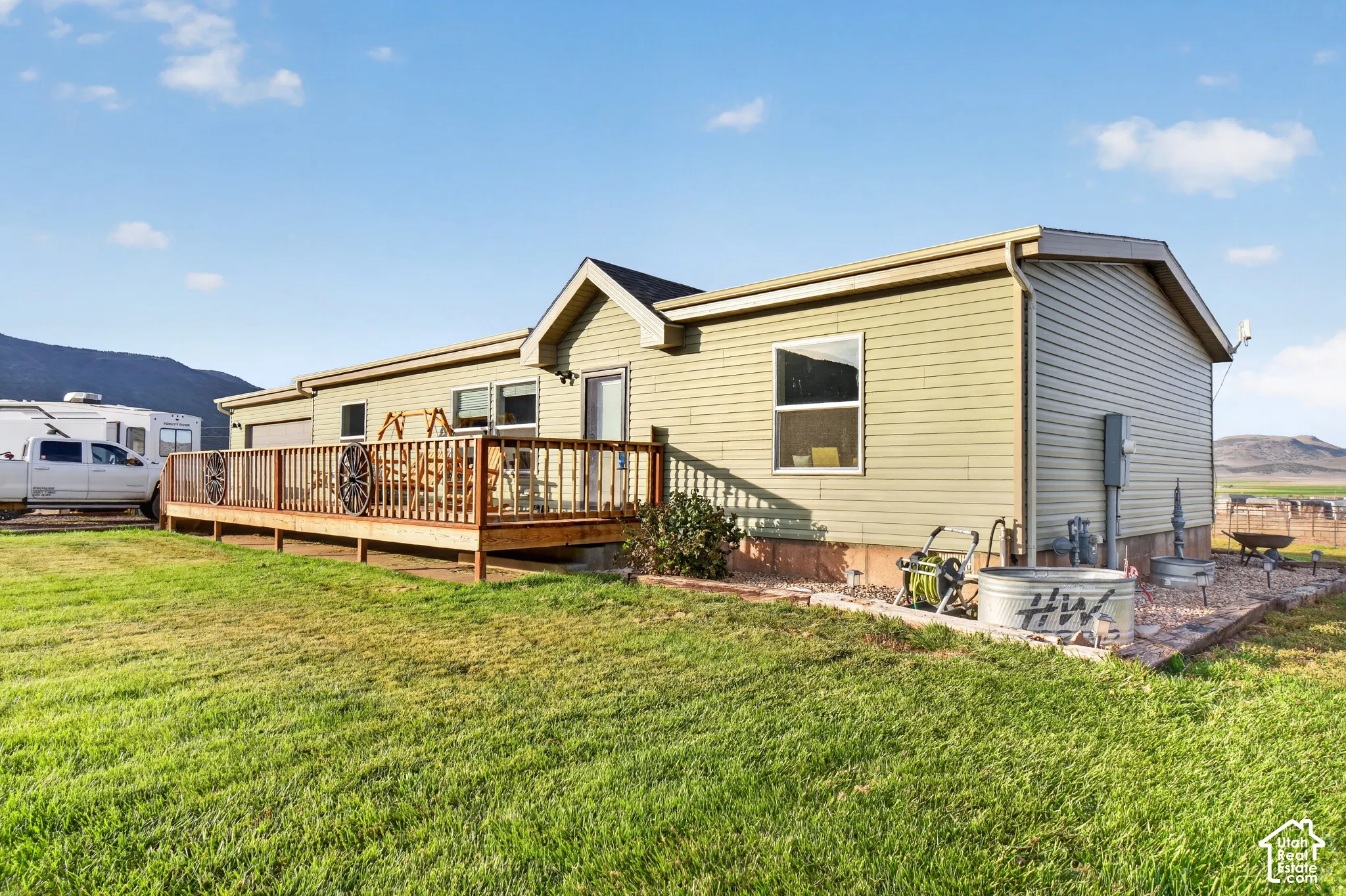 Expansive exterior featuring a wood deck, green siding, and a gabled roofline
