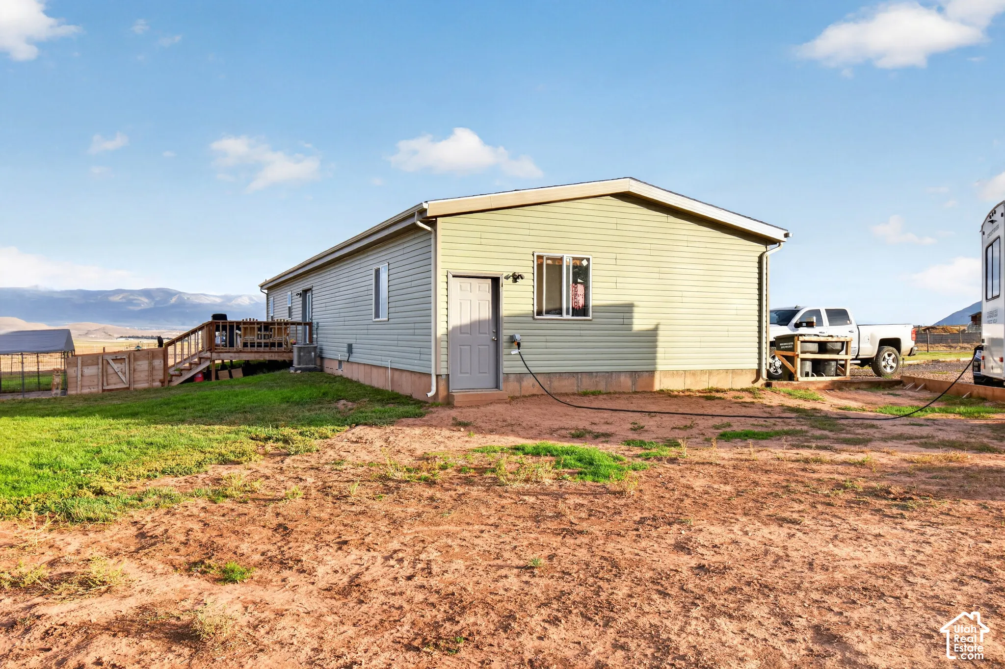 Light green siding exterior, rear wooden deck, concrete foundation, and a metal rain gutter system